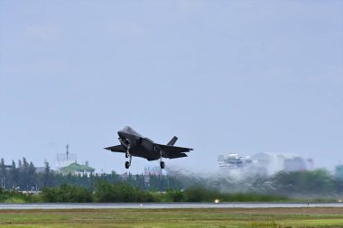 Tayland hava gösterisindeki F35a Lightning2 'nin Tayland' ın hava üssünden kalkış anı. Güçlü jet motoru uçağın arkasındaki ısı ve dumanı salıyor..