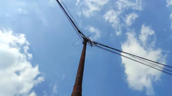 Aşağıdan gelen bir elektrik direği. Parlak mavi gökyüzü ve güzel beyaz bulutlar.