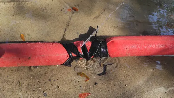 Su sızdıran kırmızı bir boru.