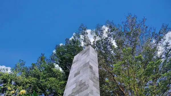 Mavi gökyüzü arkaplanı ve ağaçları olan taş bir anı.