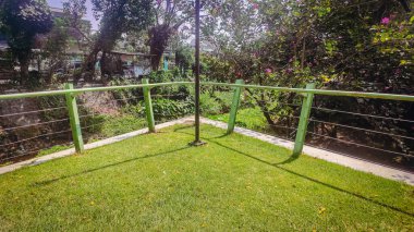 Bahçenin çimenli bir köşesi ve demir bir çit.