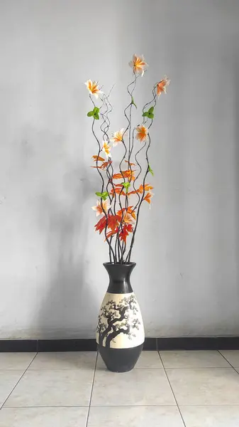 Yapay çiçek dallarıyla dolu büyük bir vazo.