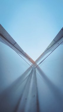 Aşağıdan görünen mimari bina simetrik olarak parlak mavi bir gökyüzü arkaplanıyla