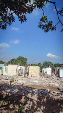 Parlak mavi bir arka plana saçılmış yıkılmış evler.