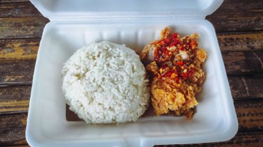 İçinde tavuk ve biber sosu bulunan geprek pilavı dolu bir yemek kutusu.