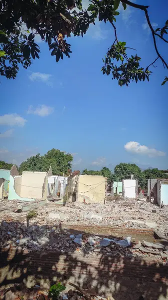 Parlak mavi bir arka plana saçılmış yıkılmış evler.