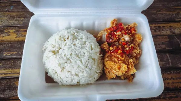 stock image a food box containing geprek rice food containing chicken and chili sauce