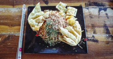 Çubuk kullanarak siyah bir kasede erişte tabağı.