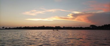 Akşamları soyut gün batımı görüntüsü. Teknesiyle oraya giden bir balıkçı. Plaj, okyanus, kızıl güneş.