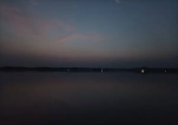 Yalnız, üzgün bir adam silueti teknenin yanında oturuyor ve elinde hareket eden suyun tadını çıkarıyor. Karanlık bir gecede.