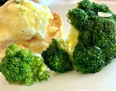 Beyaz arka planda yumurtalı Benedict ve brokolili sağlıklı bir kahvaltı.