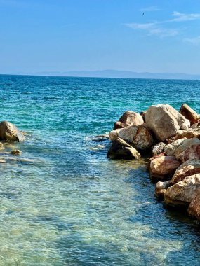 Mavi deniz, deniz taşları, dağlar