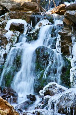 Bir dağ deresi kışın kayaların üzerinden akar.