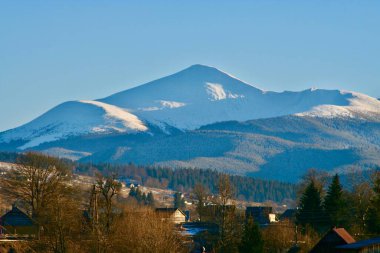 A quiet mountain village surrounded by majestic peaks and green slopes, immersed in silence and harmony with nature clipart