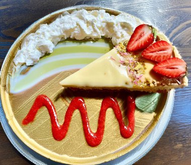 Kremalı ve taze çilekli bir dilim turta tabakta duruyor.