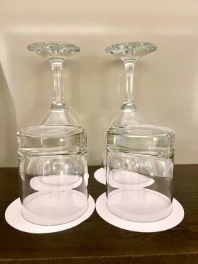 Kristal berrak bardaklar ve şarap kadehleri ahşap yüzeyde baş aşağı durur.