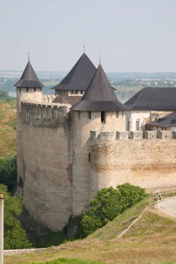 Yeşil tepelerin arka planında siyah çatıları ve mavi gökyüzünün altında bir nehri olan ortaçağ taş şatosu. Tarihsel mimari ve doğa resimsel bir görünüm yaratır..