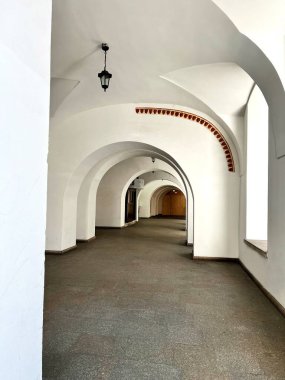 Beyaz mahzenleri ve asılı fenerleri olan antik kemer yolu. Işık ve gölge oyunu, mimari estetiği vurgulayarak derinlik ve perspektif yaratır..