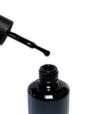 Beyaz arka planda siyah jel cilası. Açık bir şişenin üzerinde asılı duran bir damla cila ile fırçala. Manikür, tırnak bakımı ve tarz kavramı.