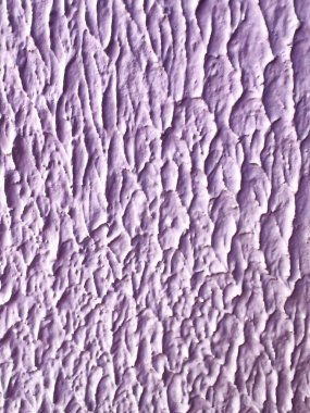 Düzensiz rahatlama vuruşları ve dokunsal bir yüzeyi olan zengin desenli lavanta alçı duvarın yakın çekimi. Kaba, organik kalıplar derinlik ve görsel ilgi yaratarak yaratıcı projeler ve tasarım şablonları için soyut bir arkaplan oluşturuyor.