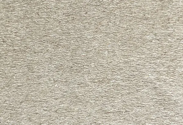 Kaba kahverengi geri dönüşümlü karton kağıdın yüksek çözünürlüklü yakın çekim görüntüsü. Görünür küçük noktalar ve ince renk değişimleriyle doğal fibröz yüzey. Çevre dostu tasarım, ambalaj modelleri ve zanaat sunumlarında kullanım için ideal