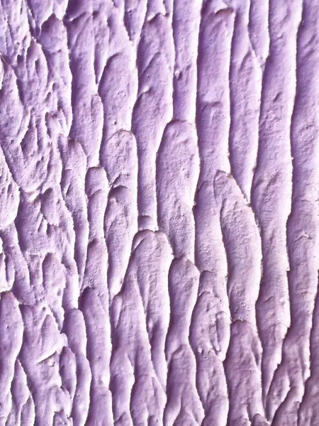 Yumuşak lavanta rengine boyanmış soyut alçı duvar dokusunun yakın çekimi. Yüzeyde sanatsal boya ya da alçı desenlerine benzeyen kalın, dikey rahatlama vuruşları var..