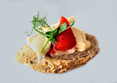 Yumuşak peynirli lezzetli aperatif, taze çilek ve çoklu tahıllı ekmek diliminde yeşil otlar. Hafif arka planda lezzetli atıştırmalık ya da gurme sandviç.