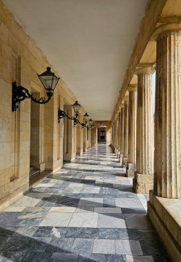 Mermer döşemeli dış geçit süslü demir duvar lambaları ve oymalı taş sütunlar.