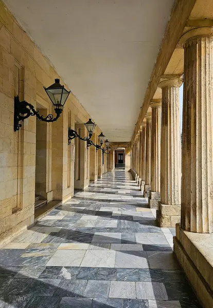 Mermer döşemeli dış geçit süslü demir duvar lambaları ve oymalı taş sütunlar.