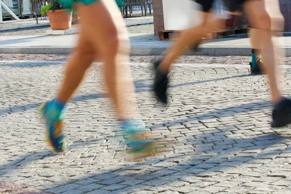 2024 'te Vilnius sokaklarında sabah ışığında maraton koşucularının bacakları ve ayakları hareket bulanıklığı. Yüksek kalite fotoğraf