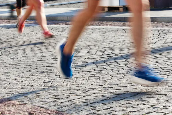 2024 'te Vilnius sokaklarında sabah ışığında maraton koşucularının bacakları ve ayakları hareket bulanıklığı. Yüksek kalite fotoğraf