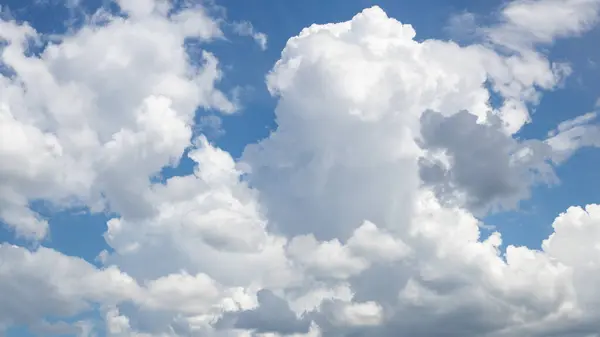 Kabarık bulutlarla dolu bulutlu mavi bir gökyüzünün parlak fotoğrafı.