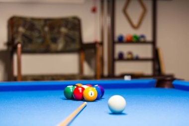 The photo shows a billiard table with a neat arrangement of billiard balls resting on the blue felt surface. The vibrant colors of the balls red, yellow, blue, green, and black stand out against the smooth, rich blue backdrop. 