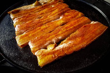 Çelik bir plancha üzerinde domuz göbeği ile barbekü.