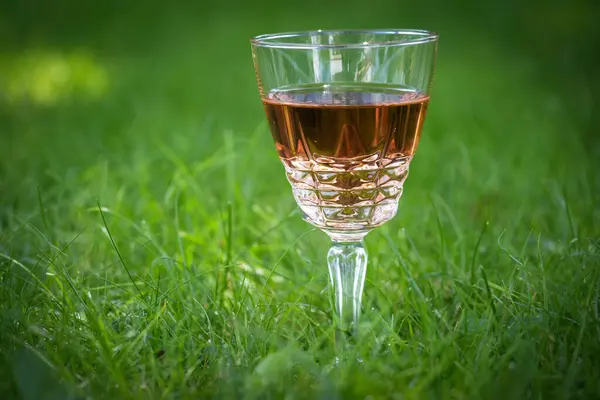 stock image Concept of a rose wine glass on a green meadow