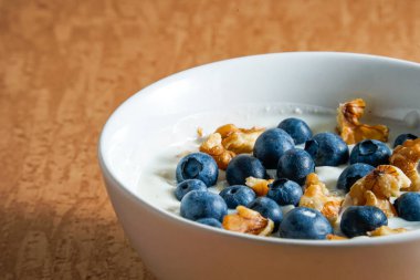 Kahverengi bir zemin üzerinde taze yaban mersini ve cevizli yoğurt ve metin alanı olan kavramsal fotoğraf.