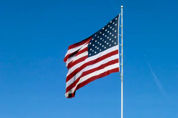 Mavi gökyüzü ile izole edilmiş bir direkte Amerikan bayrağı ve çizgileri 