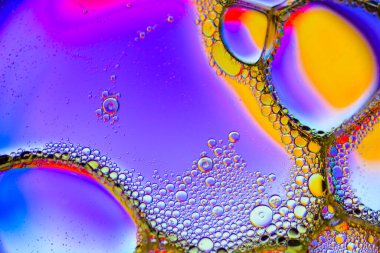 Psikedelik renklerde parlak bir yüzeye renkli su damlaları düşer