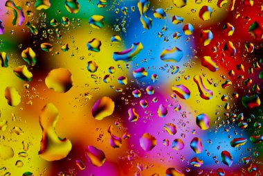 Psikedelik renklerde parlak bir yüzeye renkli su damlaları düşer