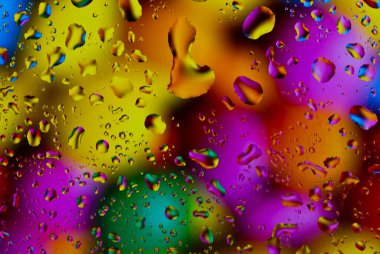 Psikedelik renklerde parlak bir yüzeye renkli su damlaları düşer