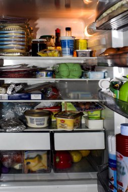 View into an illuminated refrigerator filled with food clipart