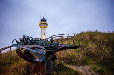 Egmond aan Zee , North Holland, Netherlands. Architecture . Landmark of Egmond aan Zee. Van Speijk lighthouse at dusk with sculptur of Louk van Meurs.Tribute to the North and South Holland Rescue Society. November 9th, 2024 clipart