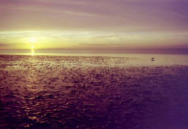Norddeich, Doğu Frizya, Almanya. Kuzey Denizi kıyısında gün batımı. 35 mm 'lik bir filmde analog retro görünüm fotoğraflandı. 9 Ekim 2024