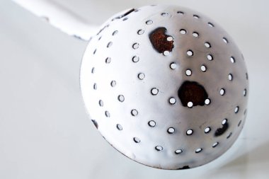 Mutfak gereçlerinin üzerinde nesne fotoğrafı olarak delikleri olan antika kepçe.