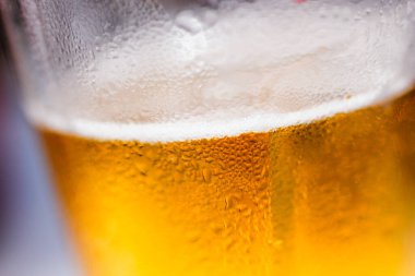 Güneş ışığında altın gibi parlayan bira bardakta ya da bira kafalı kupa