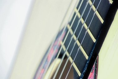 Klasik akustik gitarın sanatsal yakın çekimi. Telleri, ahşap dokuyu ve kıvrımları gösteriyor. Yaratıcı veya editörel kullanım için soyut müzik konsepti ve enstrüman ayrıntıları