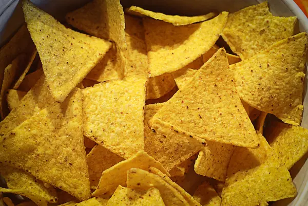 Yakın plan altın, çıtır çıtır nacho cipsi. Fast food, abur cubur, parti yemeği veya Tex-Mex mutfağı gibi kavramlar için mükemmel desenli abur cubur.