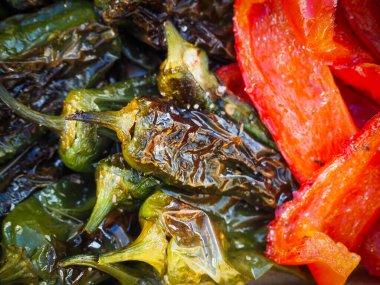 Kızarmış Pimientos de Padron ve kırsal seramik bir tabakta servis edilen kırmızı biberler. Zengin dokusuyla otantik bir Akdeniz mezesi.