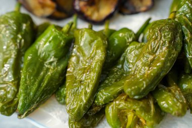 Patlıcan dilimli bir tabak kızarmış Pimientos de Padron. Lezzetli bir İspanyol usulü aperatif taze ve kırsal bir dokunuşla servis edilir.