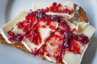 Bir kaşık dolusu meyve reçeli ile kaplanmış, kır ekmeği üzerine camembert peyniri. İnce ve lezzetli bir atıştırmalık için tatlı ve zengin peynirleri birleştiriyor.